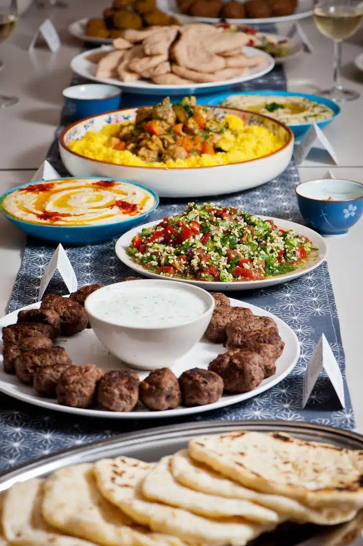 Catering table with grilled meat, salad, dips, rice, and bread